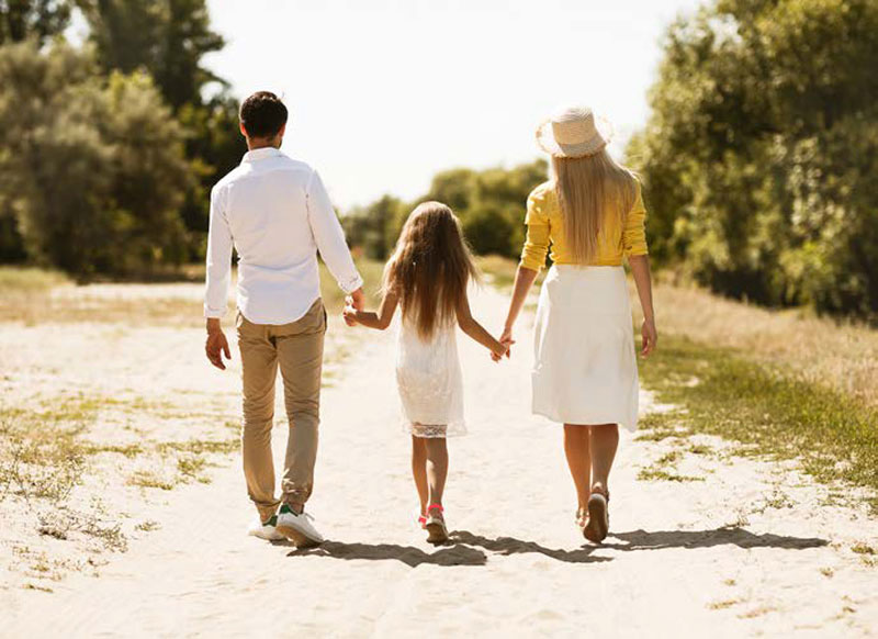 couple walking hand-in-hand with their daughter
