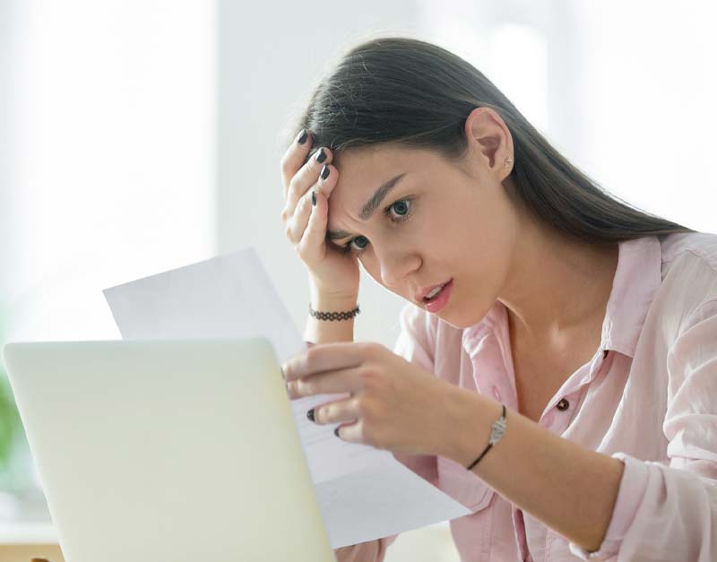 frustrated woman looking at piece of paper and holding her head