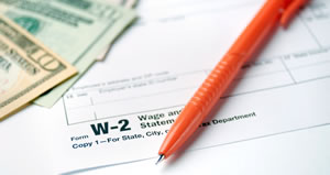 money and pen laying on IRS W-2 form
