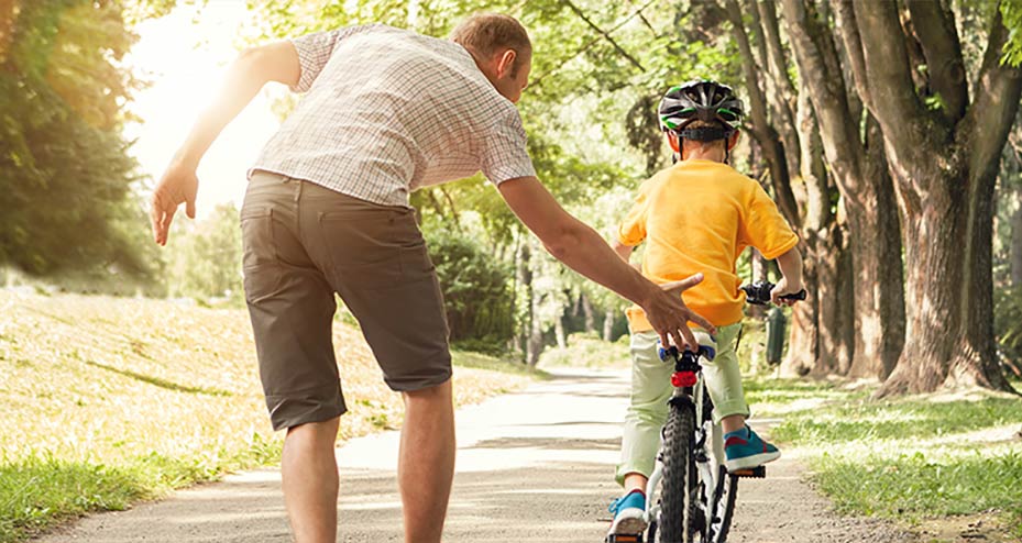 Father helping his son learn how to ride a bicycle