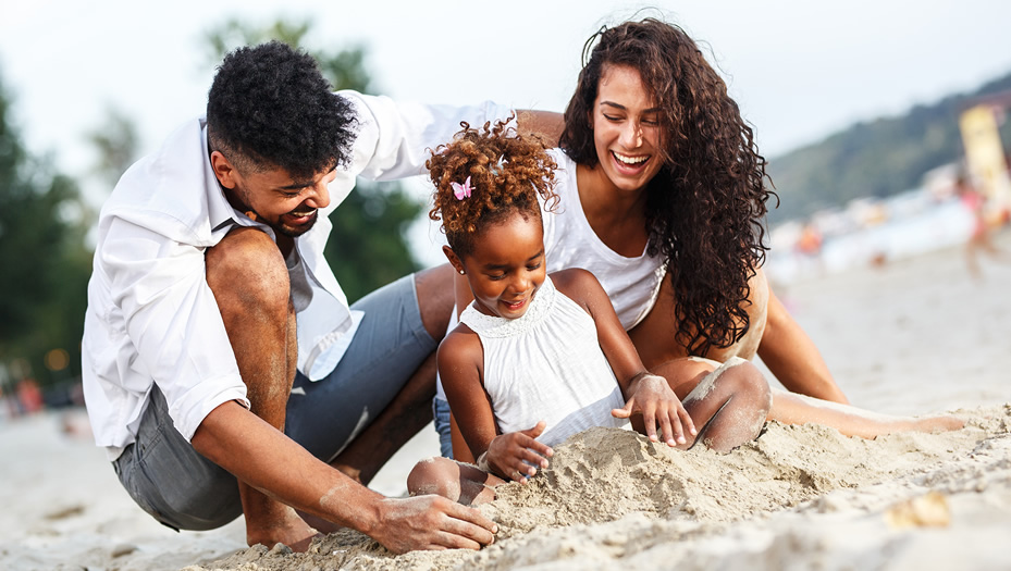 mother and father playing in sand with daughter