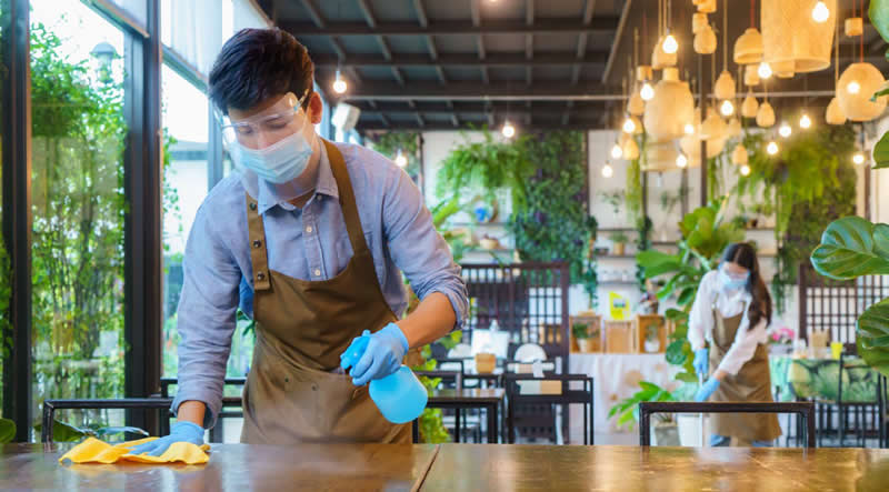 employee cleaning a table at a restaurant