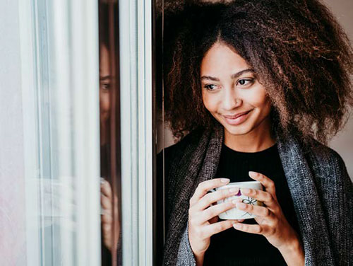 a woman holding a cup of coffee and smiling