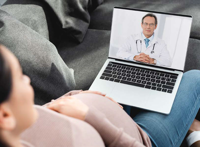 pregnant woman talking with her doctor on a laptop