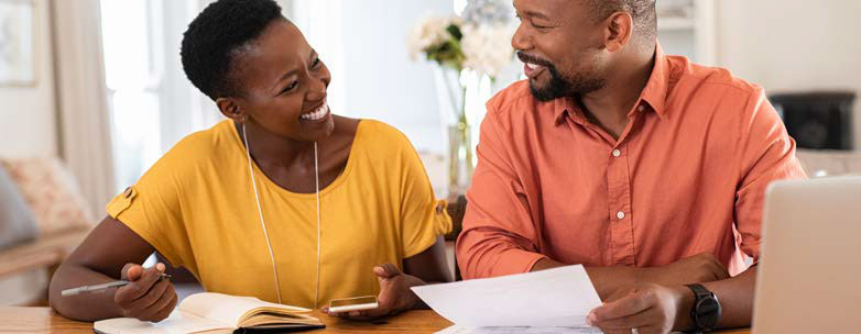 man and woman smiling while they work on paperwork