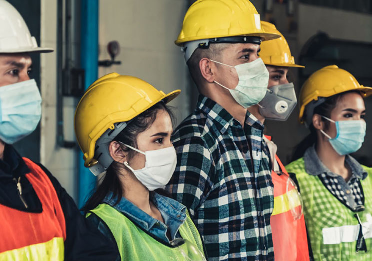 employees wear hard hats and face masks to protect themselves while working