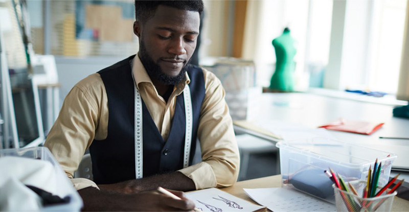 a fashion designer works ay his desk on a sketch