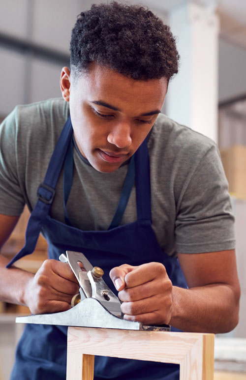 man using a wood planer on a piece of woodwork