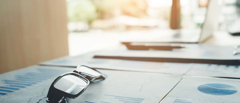 a pair of reading glasses laying on a table with charts spread out on it