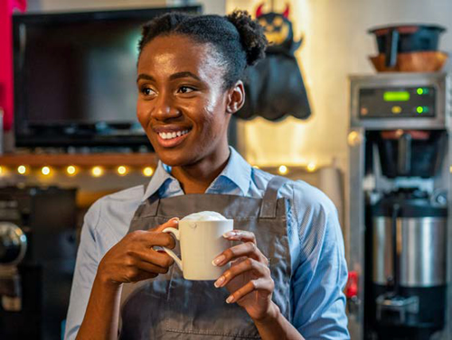 a coffee shop barista holding a cup of coffee and smiling