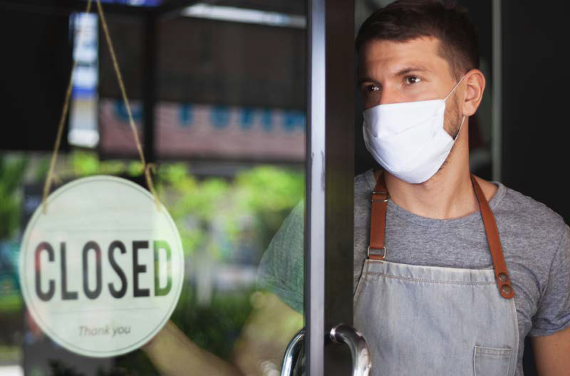 business owner standing in doorway with a closed sign