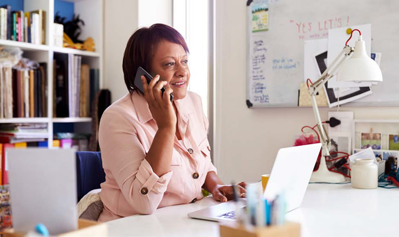 woman sitting at a desk using a telephone