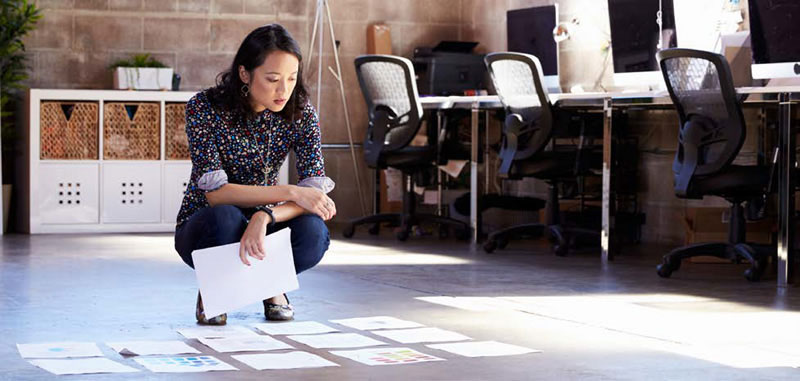 woman looking at documents spread out on the floor