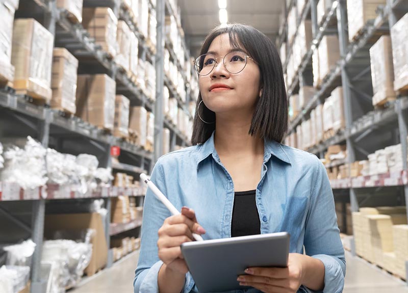 employee writing on clipboard looking up in warehouse