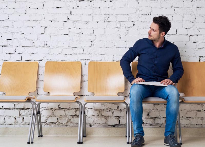 man sitting in a row of empty chairs