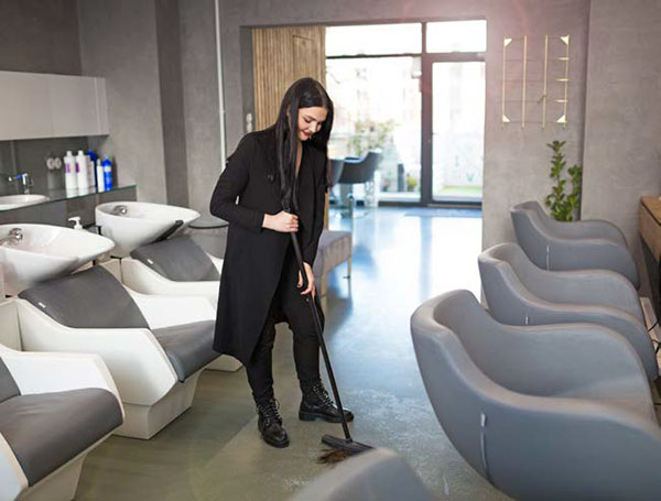 employee sweeps floor of hair salon
