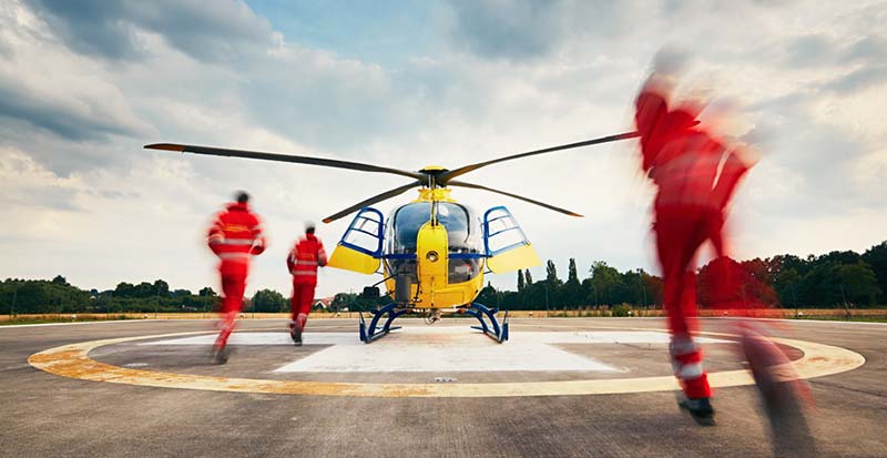 three EMS workers running toward helicopter