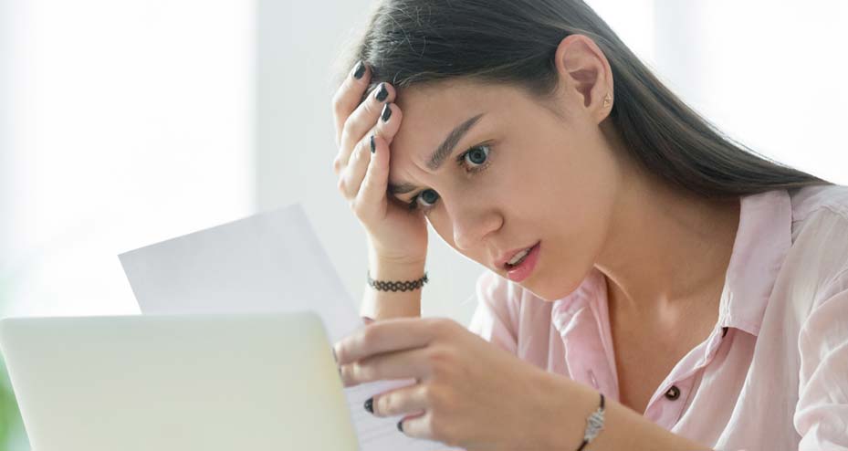 frustrated woman looking at piece of paper and holding her head