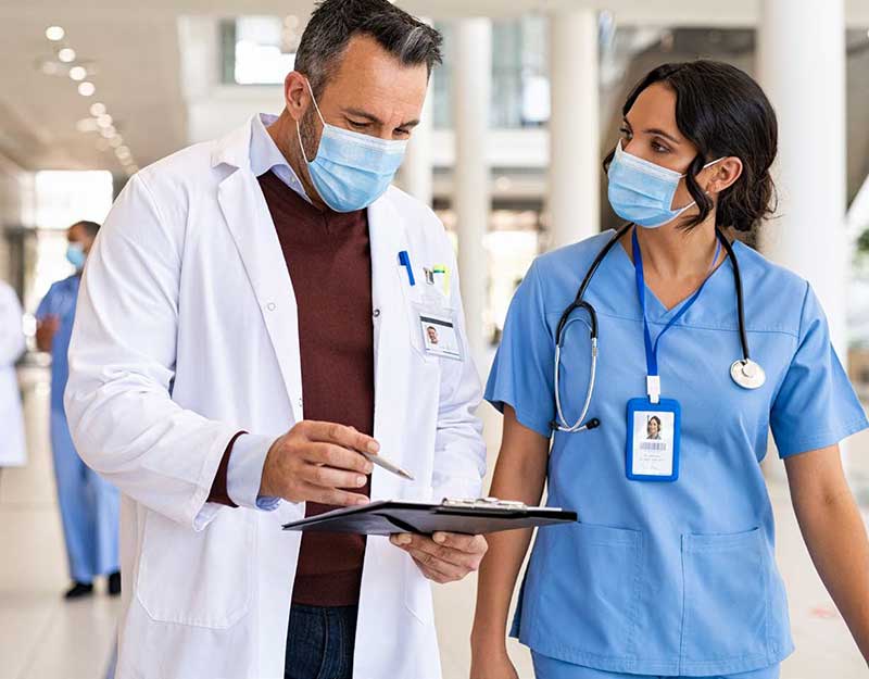 masked doctor and nurse looking at a clipboard