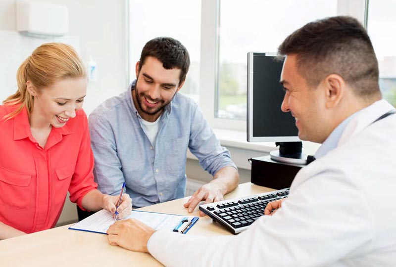 couple filling out paperwork with doctor