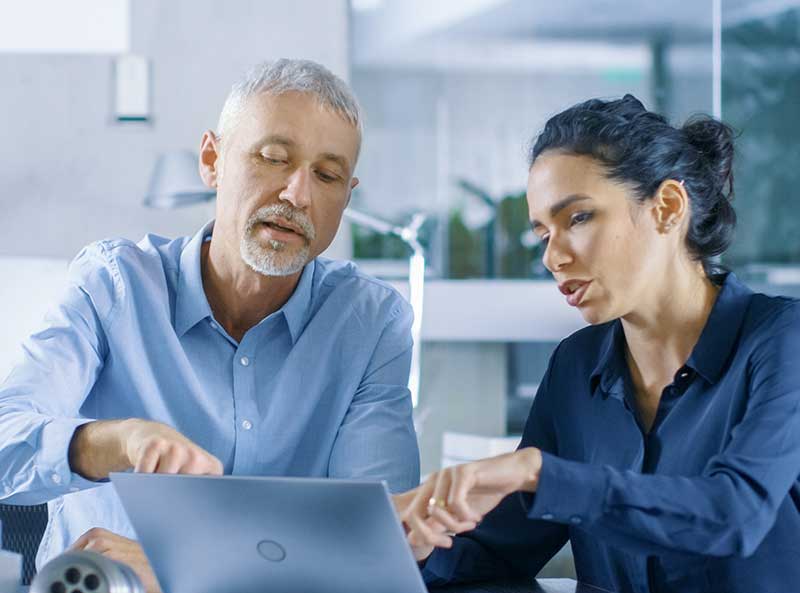 two coworkers pointing at laptop