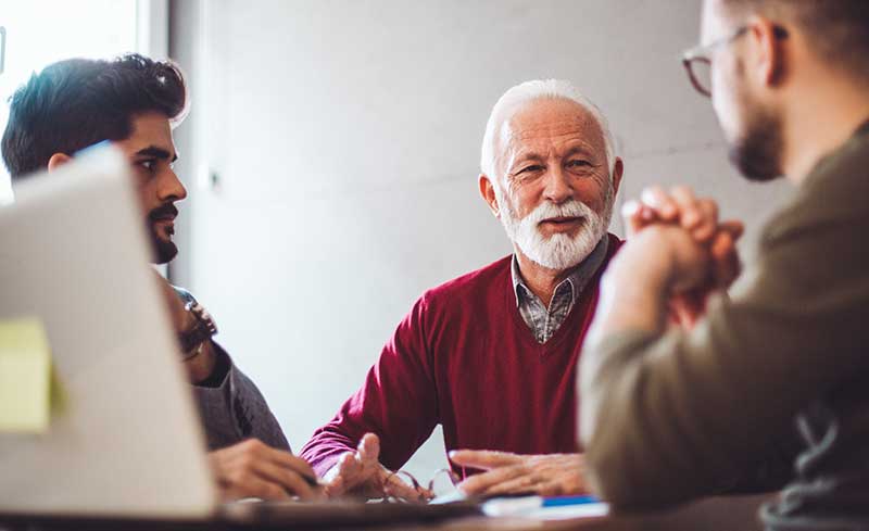 three guys talking at a desk