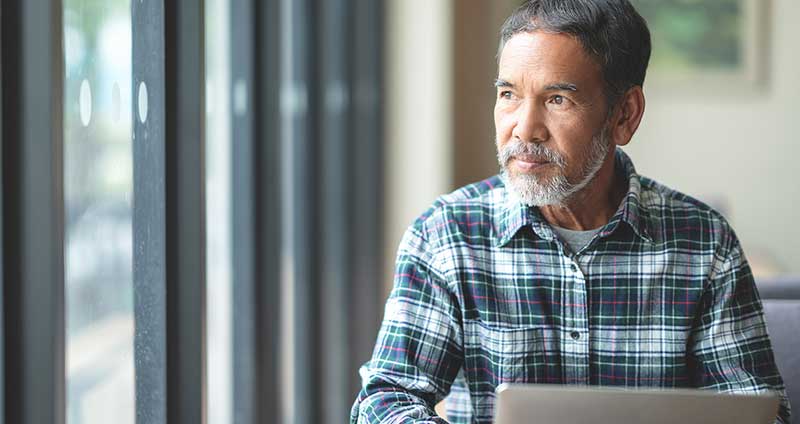 man working on laptop and looking out the window