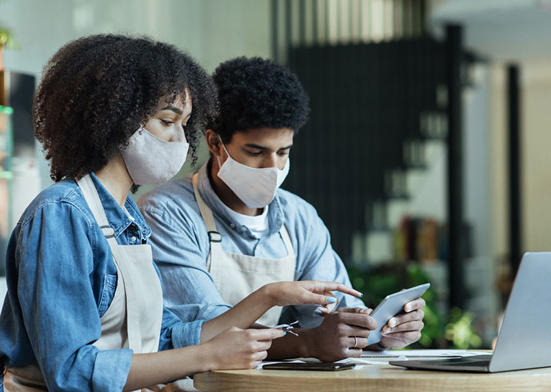 two coworkers looking at electronic devices together