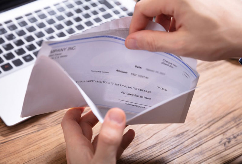 hands opening a paycheck envelope