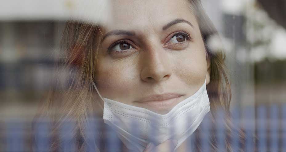 woman with mask looking out window