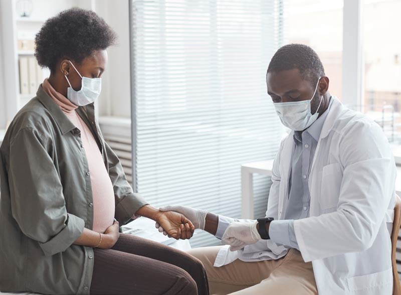 doctor counting pregnant woman's heartbeats