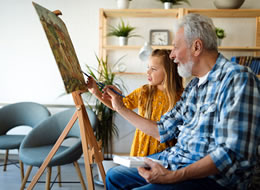 man and granddaughter painting on a canvas