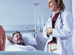 smiling man in hospital bed looking up at doctor