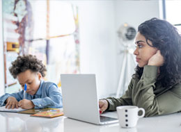 child writing and woman working on laptop