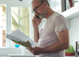 man talking on cellphone and looking at papers