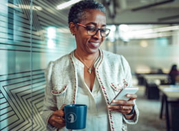 woman holding coffee mug looking at cellphone
