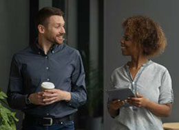 two employees walking, talking and holding coffee