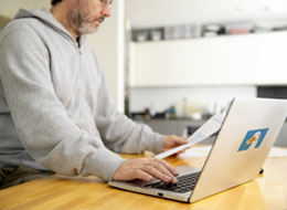 man holding paper and working on laptop