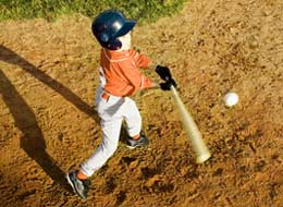boy hitting baseball with a bat