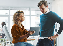 two employees talking and looking at an ipad