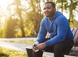 man sitting on park bench holding water bottle