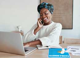 woman talking on phone and working on laptop