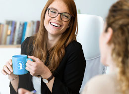 two women laughing and drinking coffee