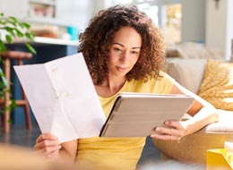 woman looking at a piece of paper and a tablet