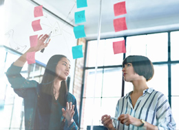 two women hanging post it notes from ceiling