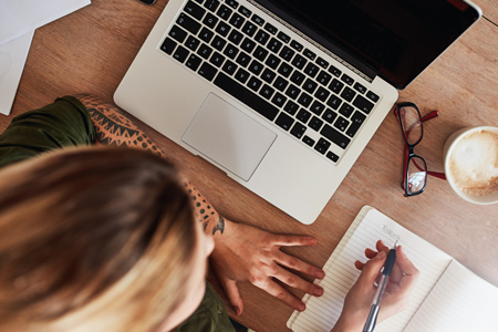 woman using laptop computer and taking notes