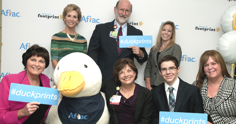 people pose with Aflac duck and #duckprints hashtag signs