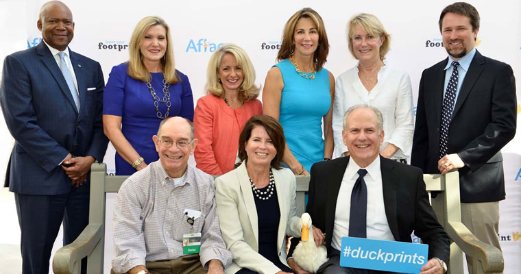 people pose with Aflac duck and #duckprints hashtag signs