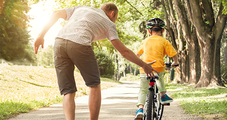 dad teaching son how to ride a bicycle