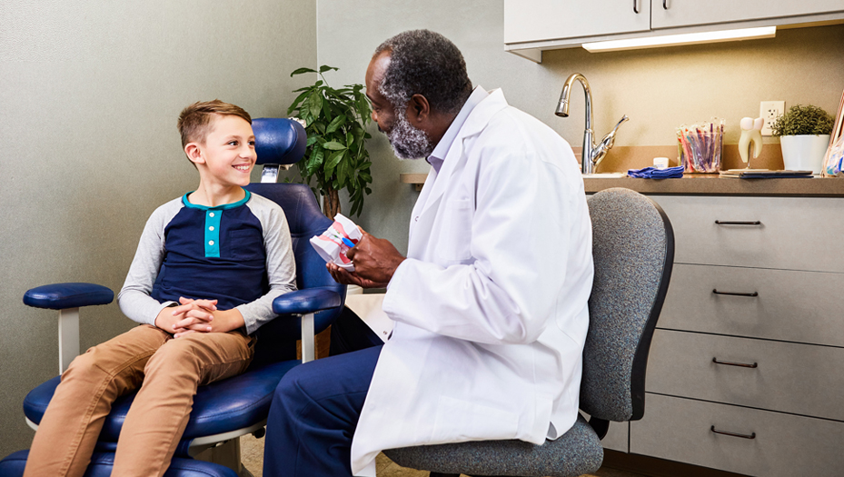 young man in dentist chair talking to the dentist